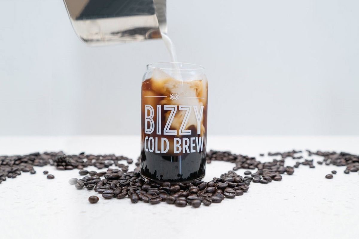 Milk is poured into a cup of Bizzy's Cold Brew. 