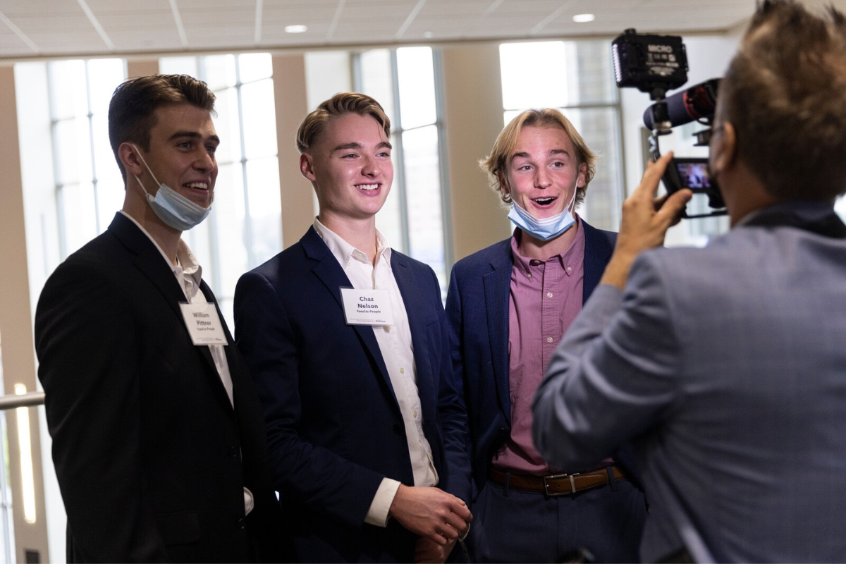 Three smiling white male students being interviewed