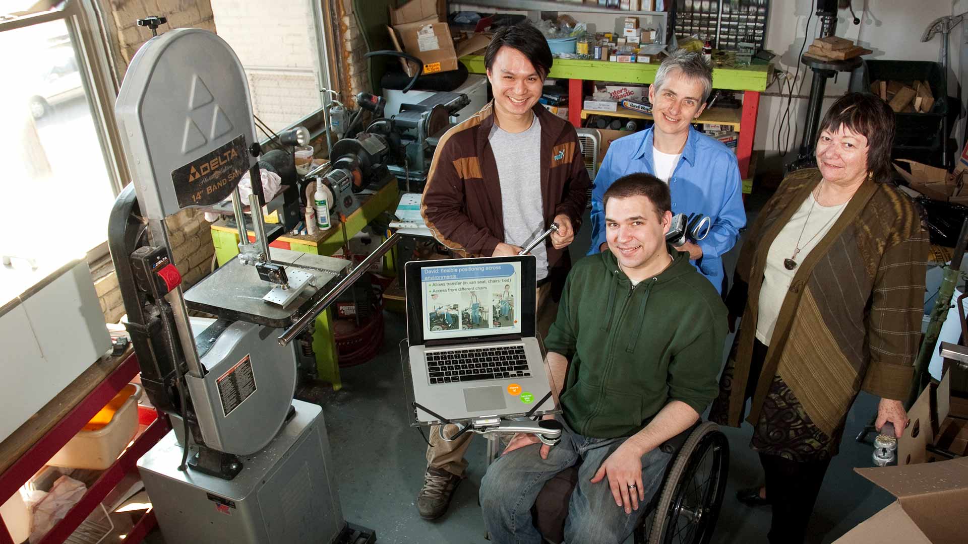 A group posing with an invention for a wheelchair attachment.
