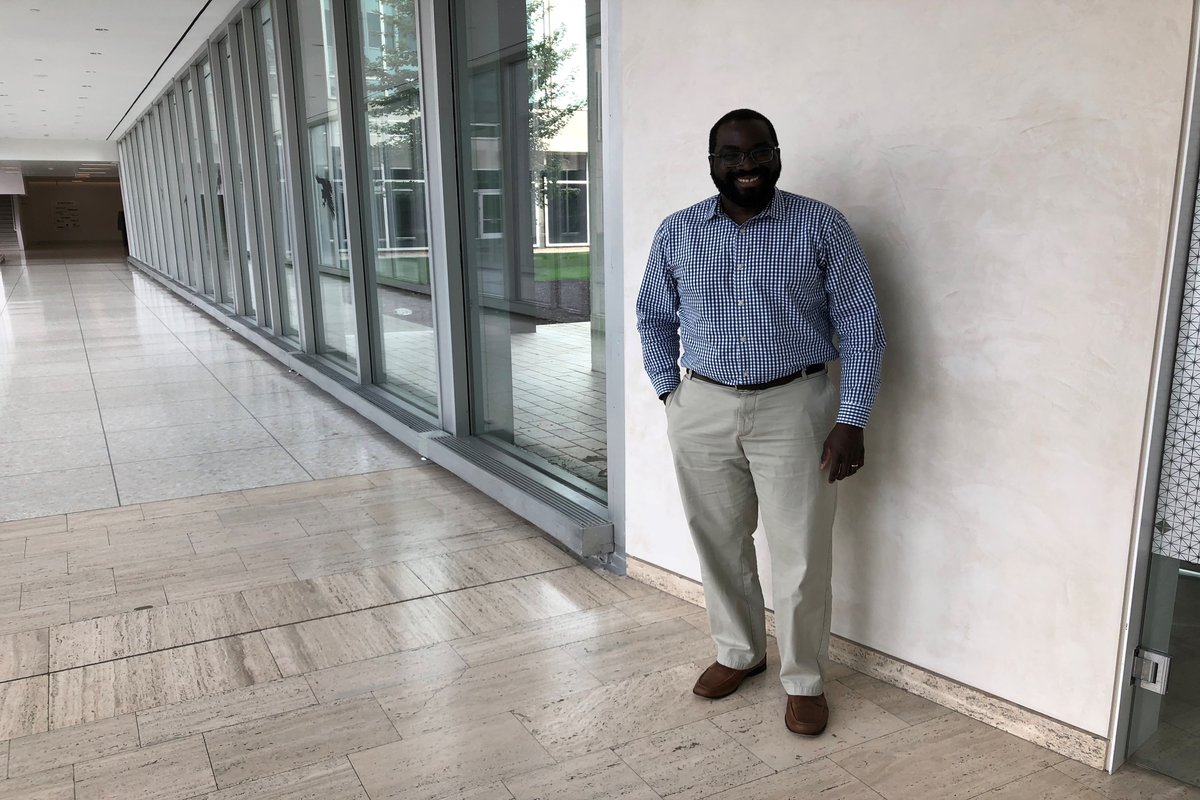 Part-time MBA graduate Lee Winbush stands in front of a sign at 3M.