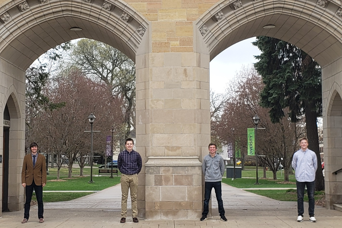 two men standing in front of the arches at the University of St Thomas