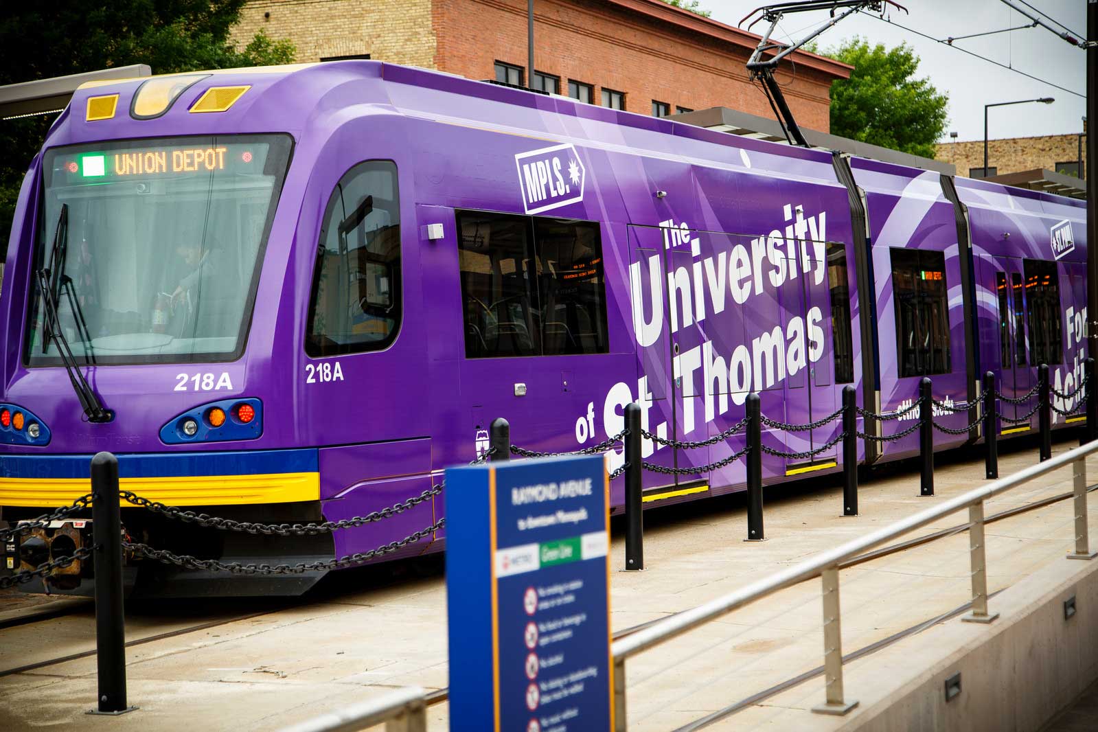 Minneapolis Lightrail with purple St. Thomas wrap comes into a station.