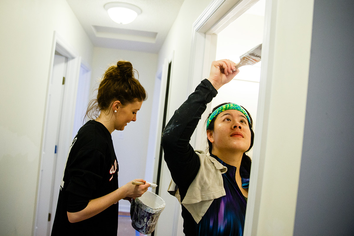 Two students painting a hallway.