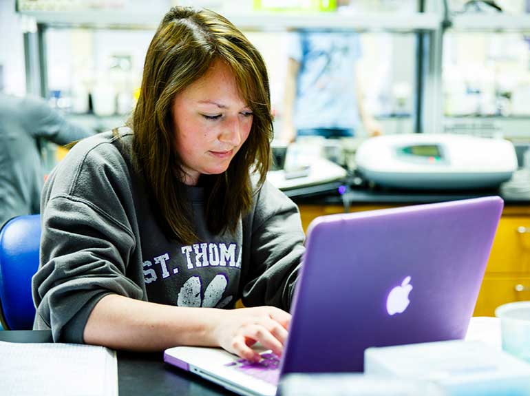 Student Tess King types on purple laptop computer during class.