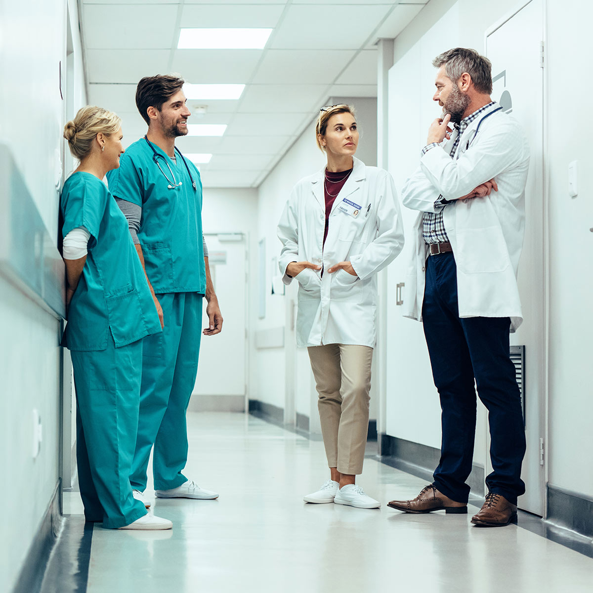 Four doctors talking in a hospital hallway. 