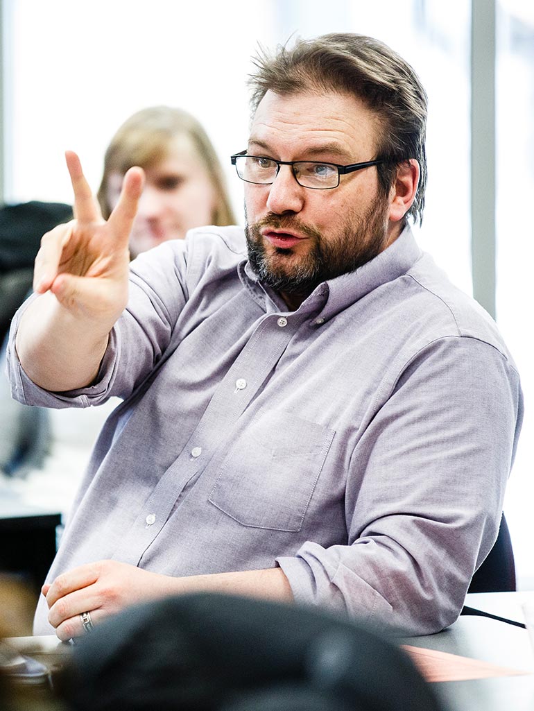 A student makes the hand signal for "two" while participating in a class discussion in the Opus College of Business in Terrence Murphy Hall.