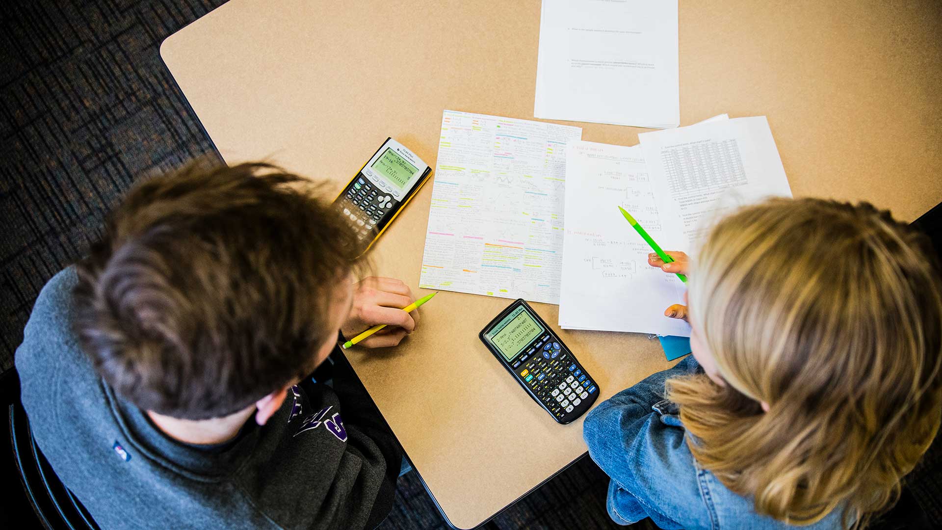 Student talk over study materials and a calculator during a staged photoshoot with Opus College of Business student tutors in McNeely Hall on March 20, 2018 in St. Paul.