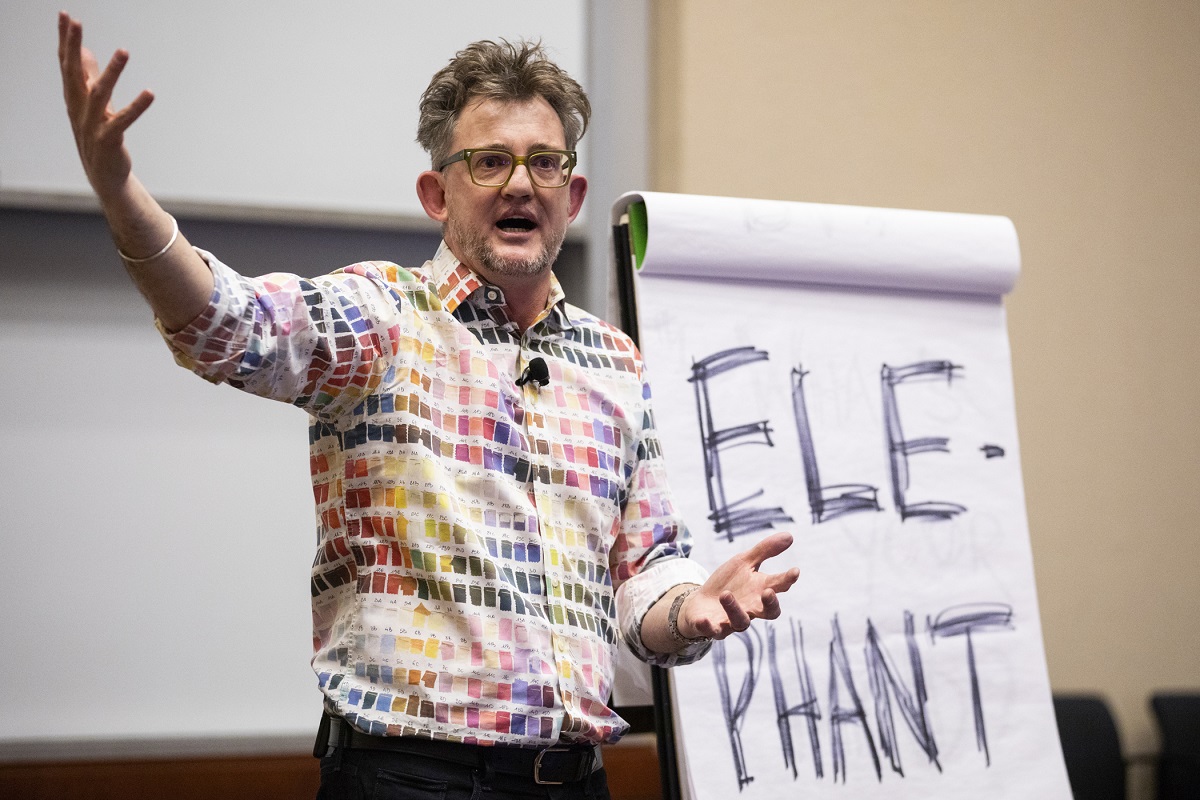Michael Bungay Stanier speaks and gestures in front of a large notepad during the Executive Coaching in Organizations Conference.