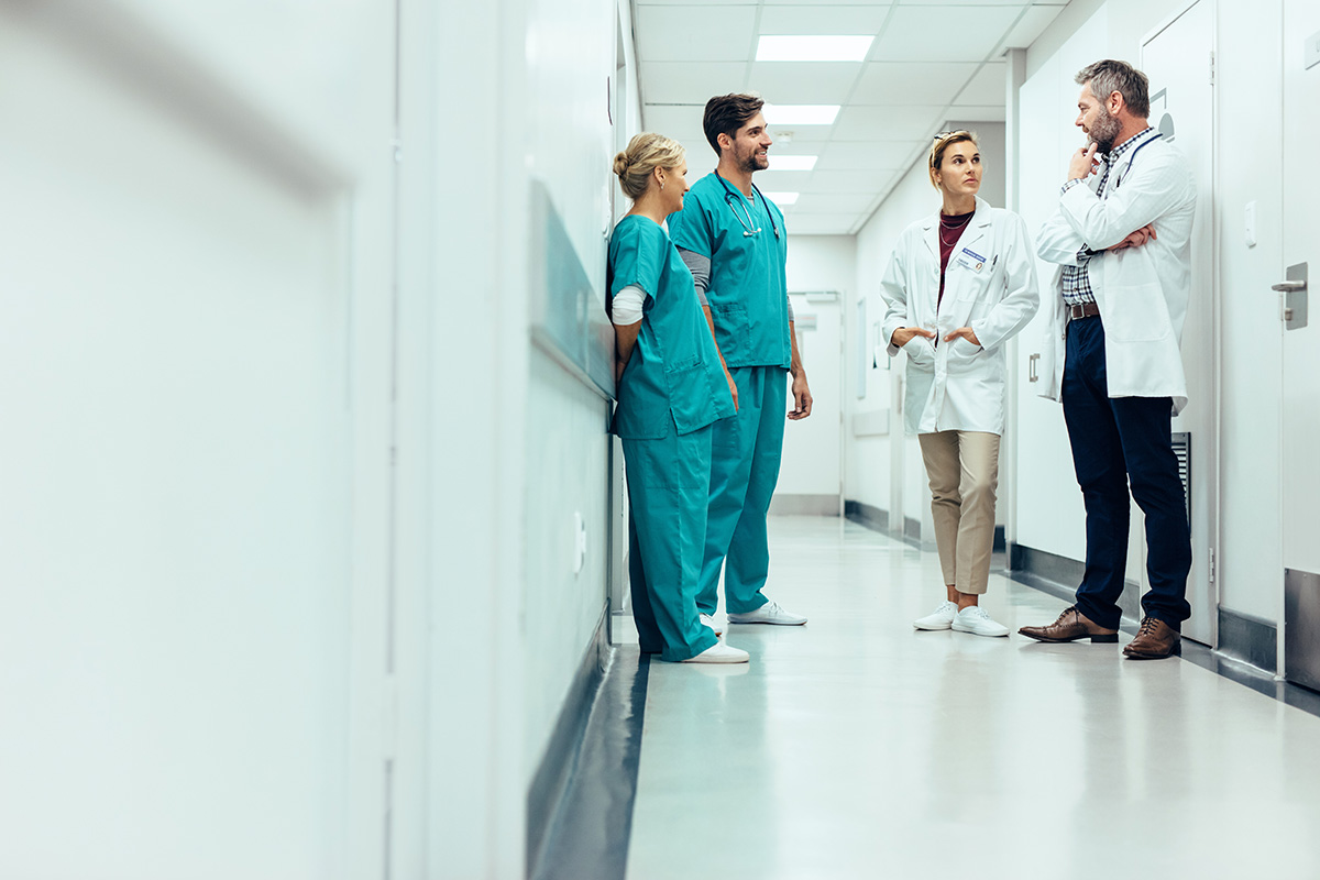 Four Health Care workers talk to one another in a hallway