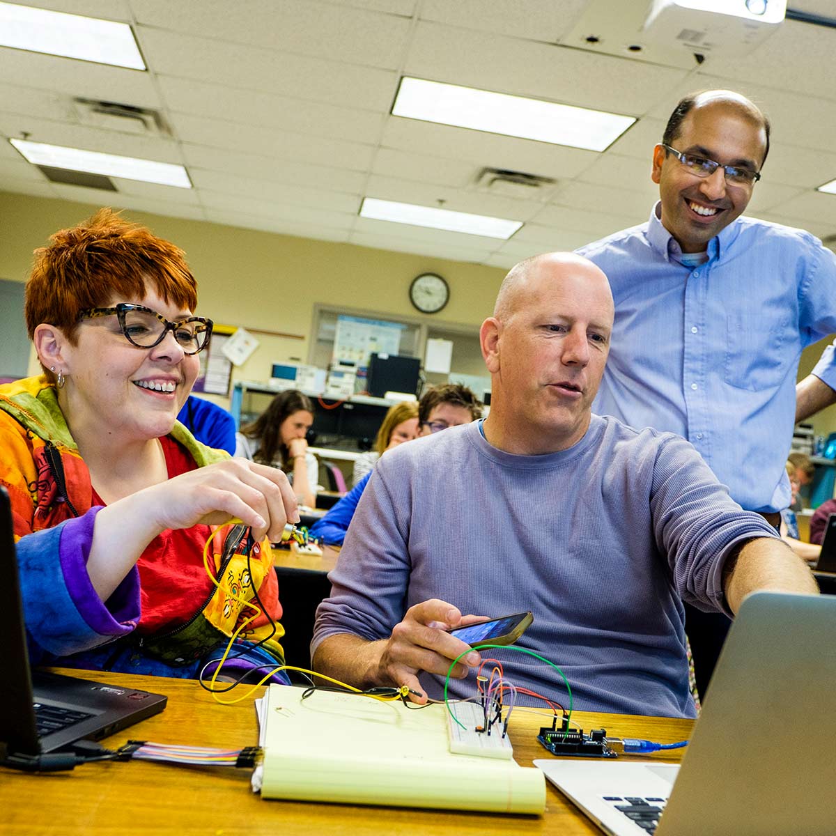 A professor (right) helps students with their project. 