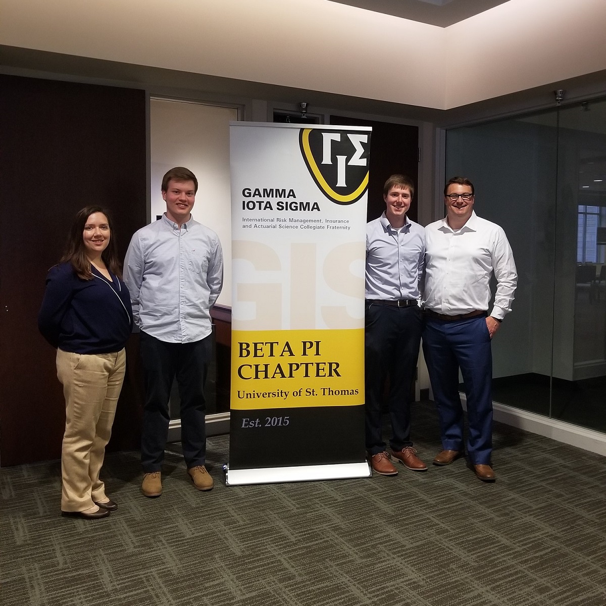 Gamma Iota Sigma participants stand next to a banner for their organization.