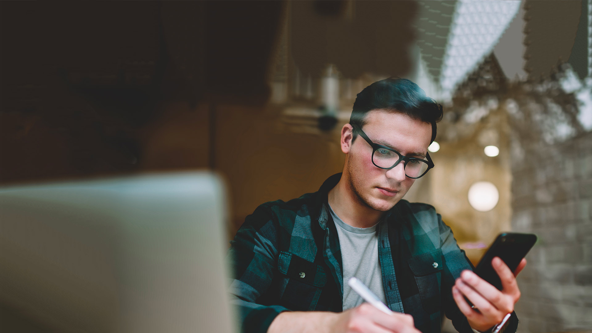 Business student using mobile phone and taking notes on a notebook.