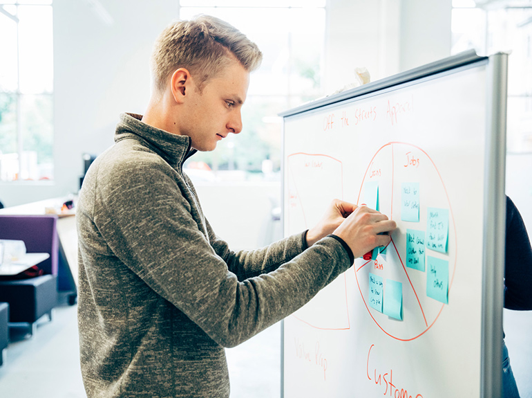 Student works on a white board at an Opus College of Business workshop.
