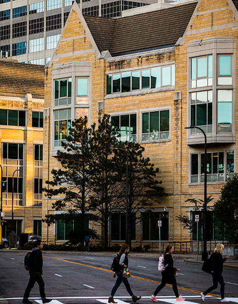 Pedestrians cross Harmon Place in front of Terrence Murphy Hall and Opus Hall in Minneapolis.
