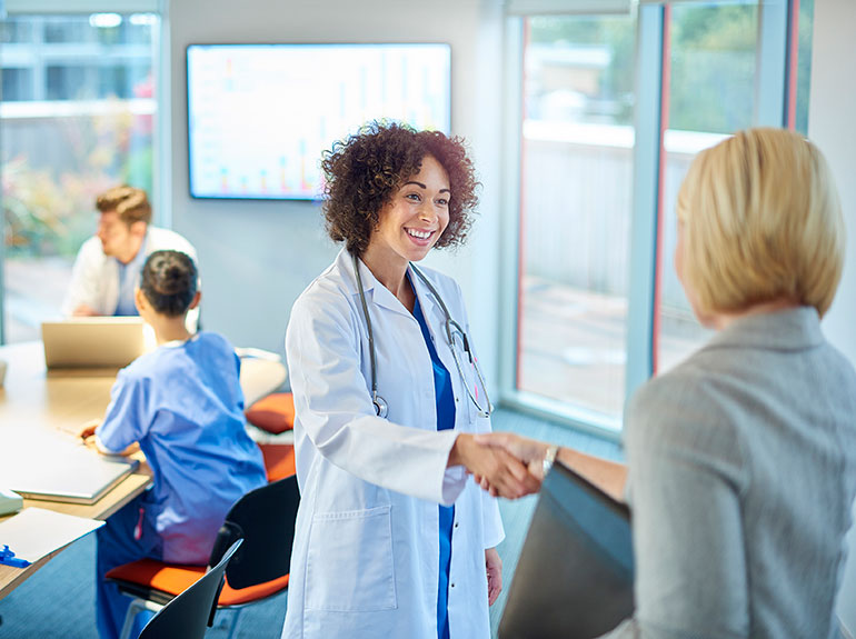 A doctor shaking the hand of an administrator inside a conference room.