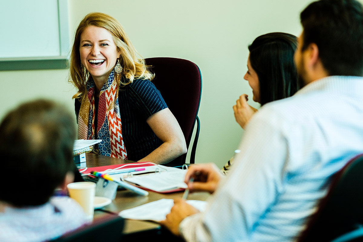 Woman at a table with others, smiling. 