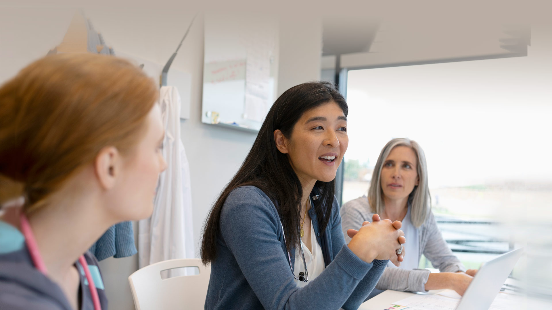 Women sitting and engaged in discussion around a white desk.