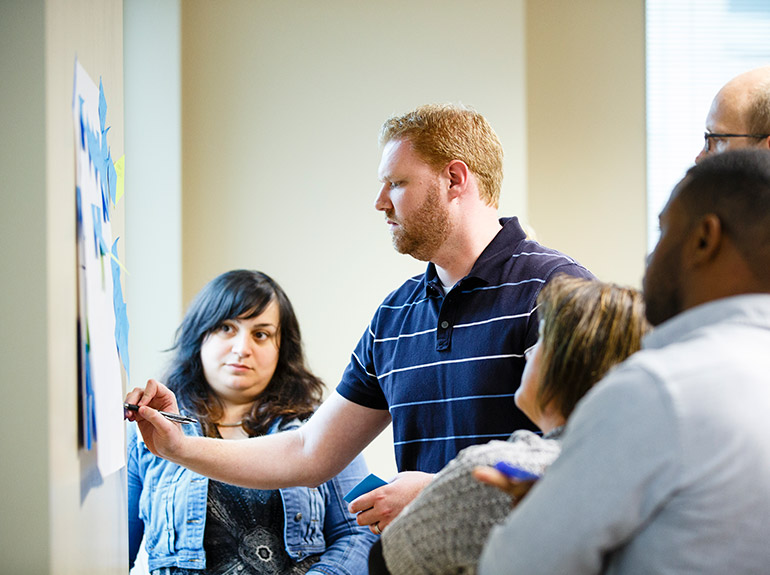 Students working together on a poster covered in post-it notes