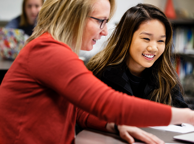 A student smiles as she gets help with homework in a campus resource center. 