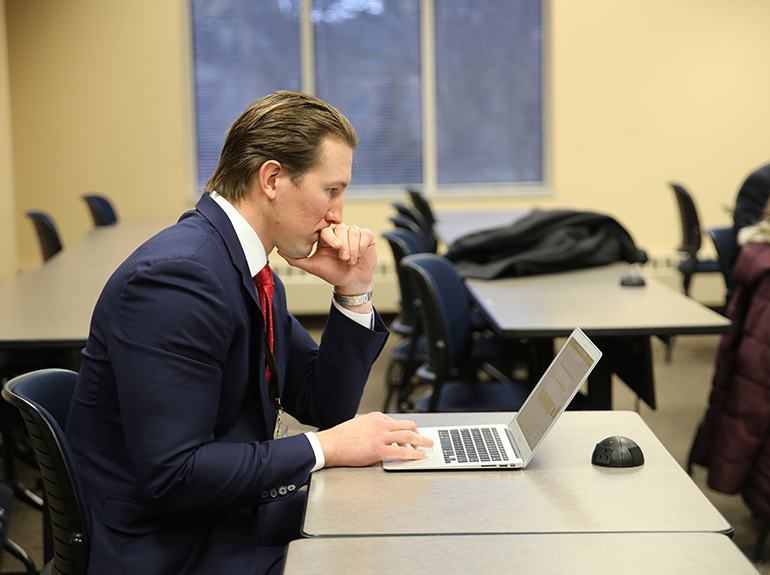 Student in class with his laptop looking pensive.