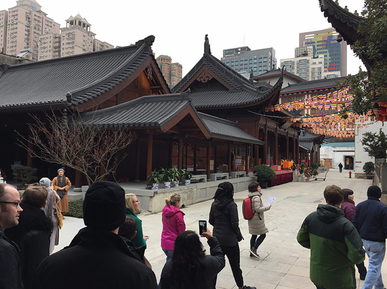 A group of tourists walks by and snaps photos of the Yufo Temple in Shanghai.