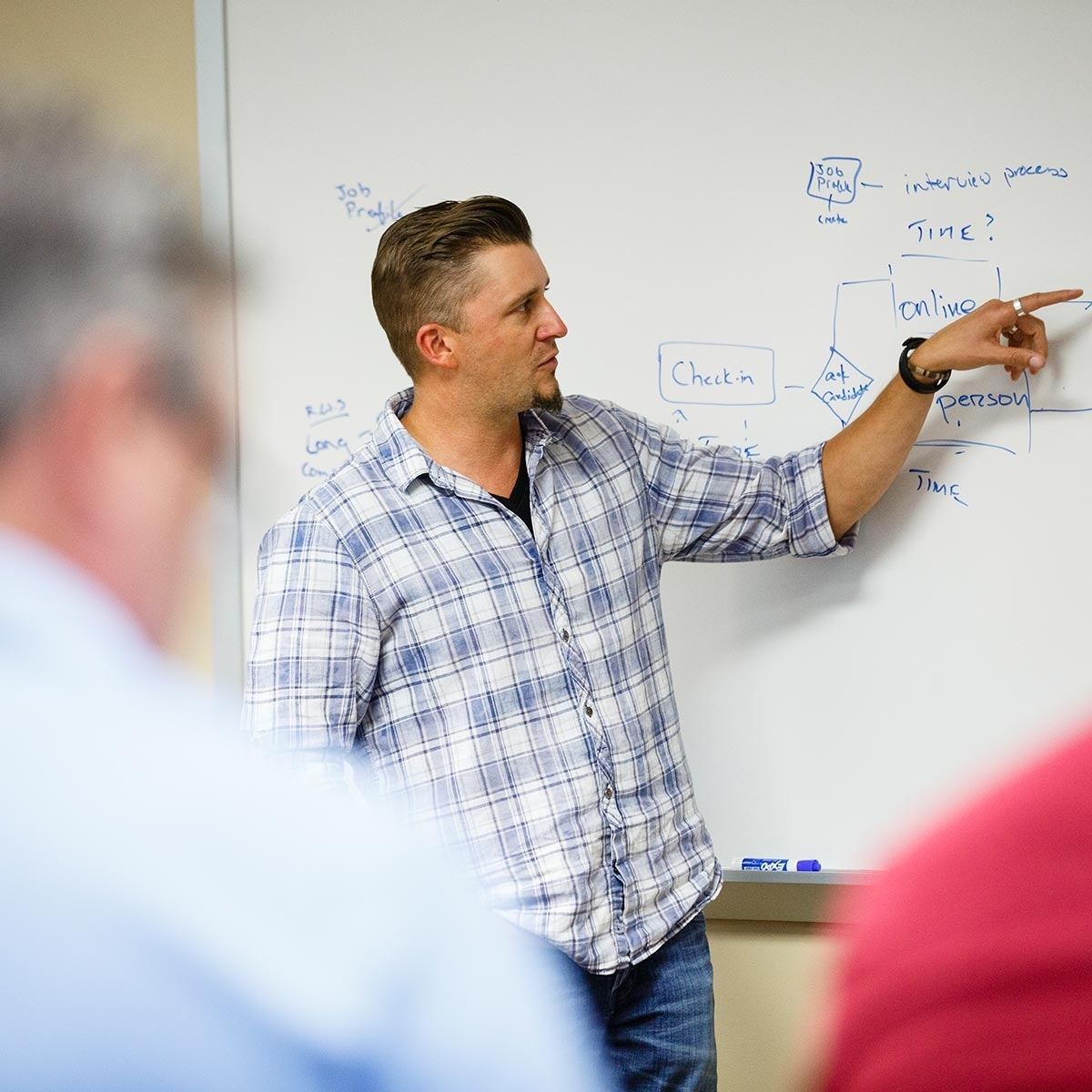 An Opus College of Business student points at a white board as he explains something to the class.