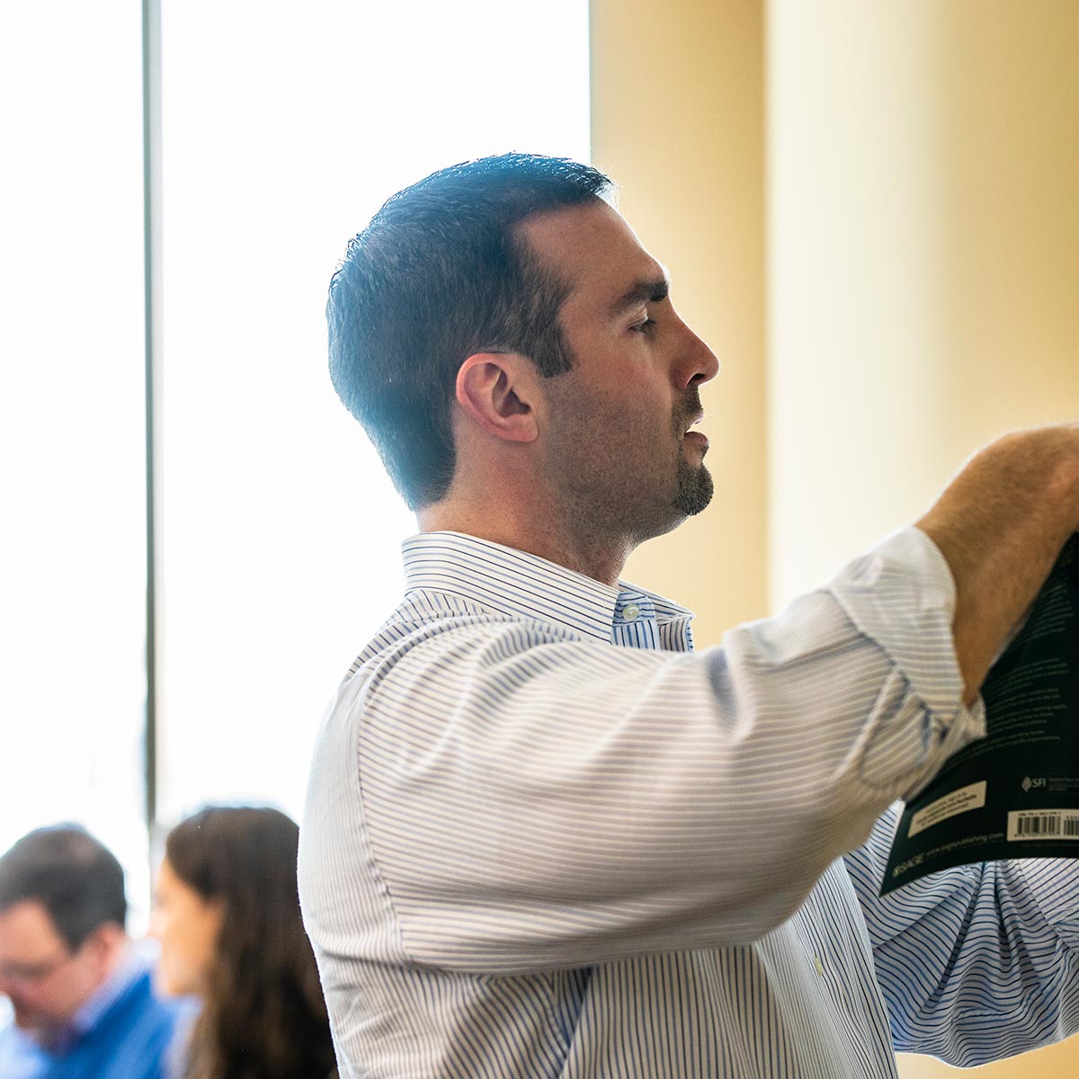 A student writes on a paper while holding a book during an Executive MBA Class.