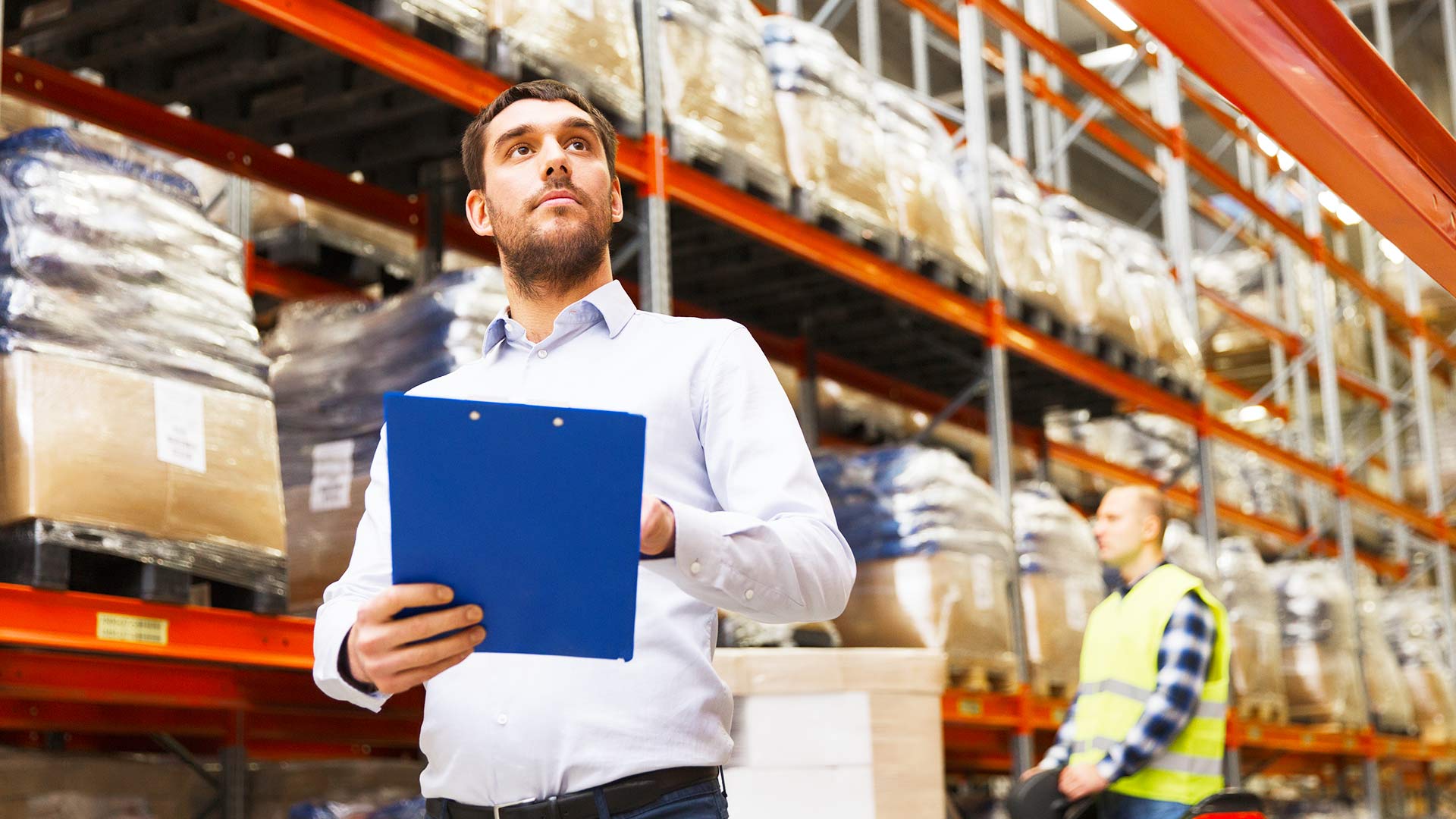A professional with a clipboard in a warehouse.