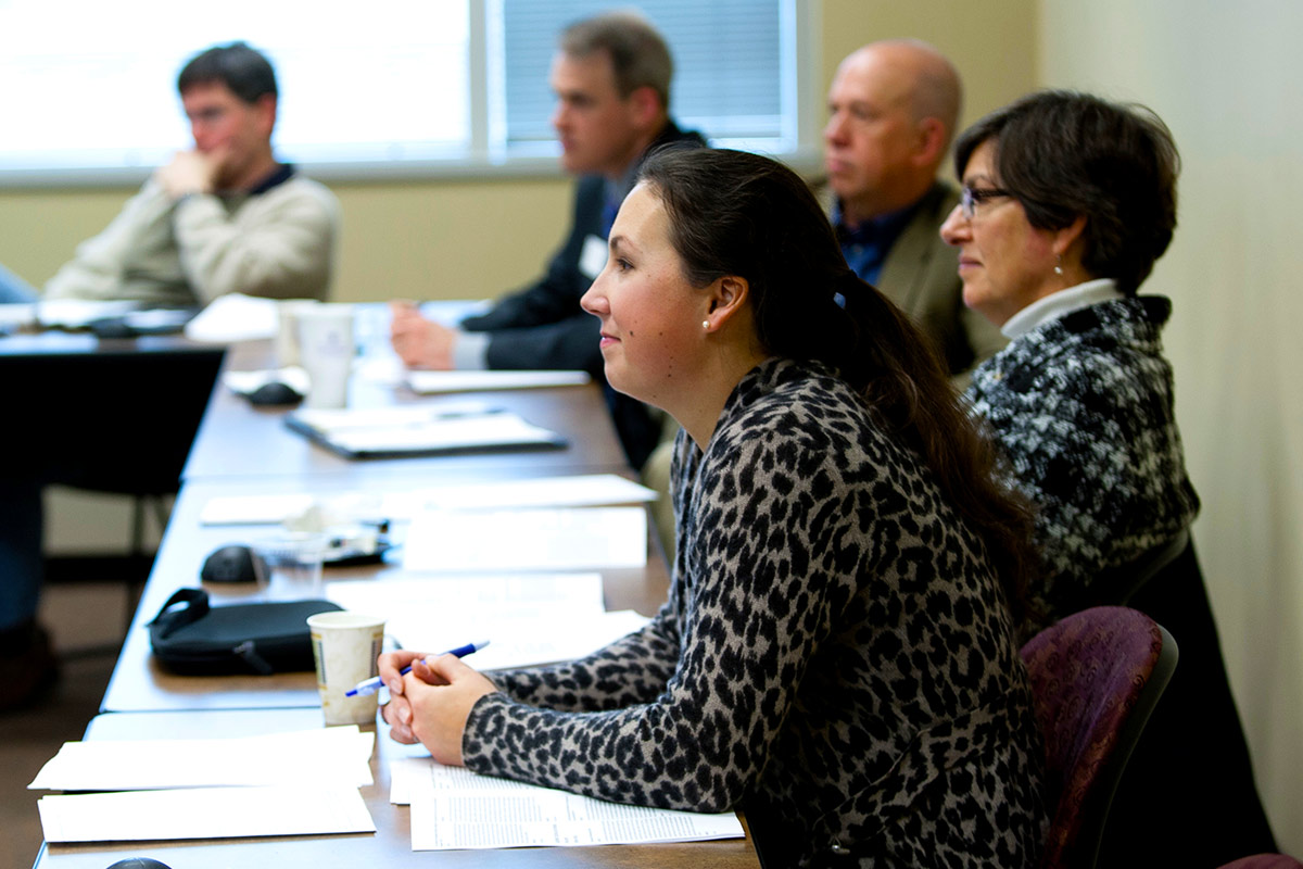 Faculty looking intently and listening to a research discussion.