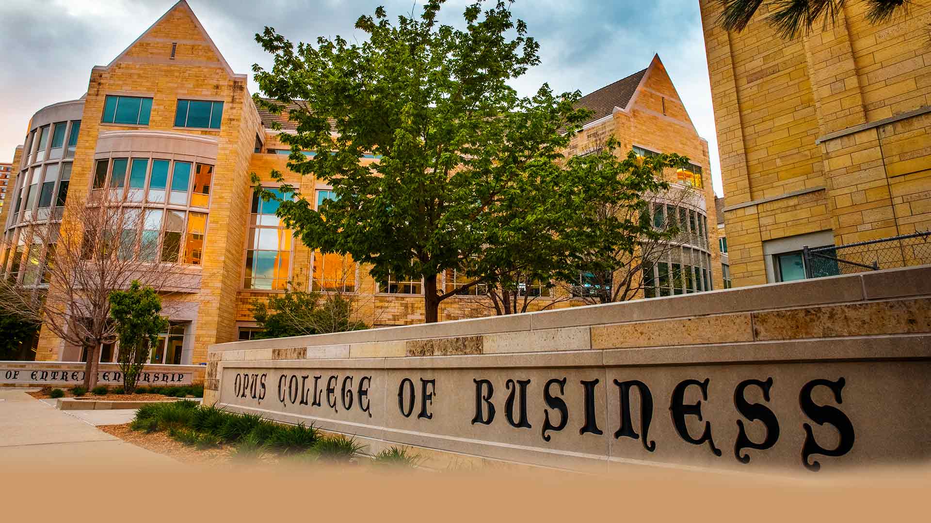 Opus College of Business masonry sign on a cloudy day.