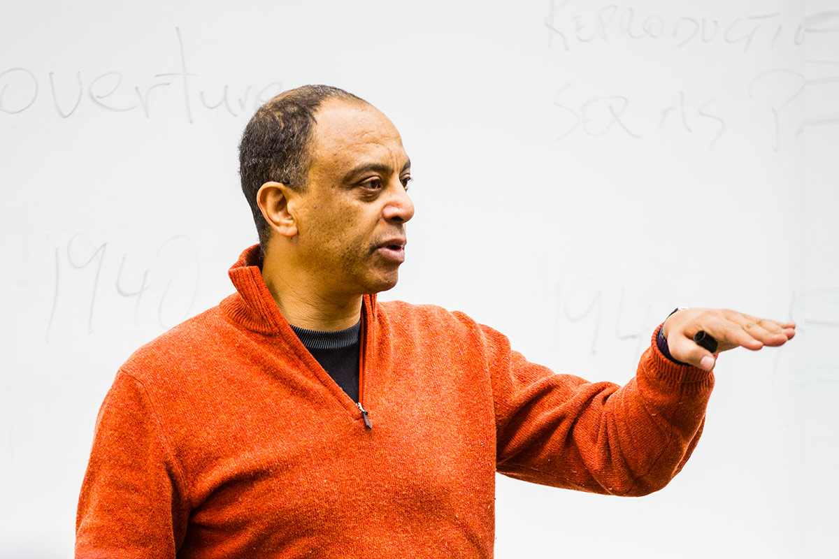 Instructor teaching individuals with a whiteboard behind him.