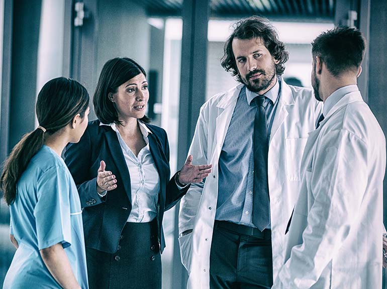 Doctors and nurses talking to each other in a hospital room.