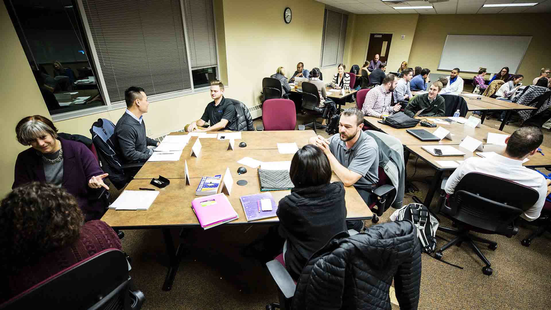 Students engaged in discussion with their respective groups at a round table.