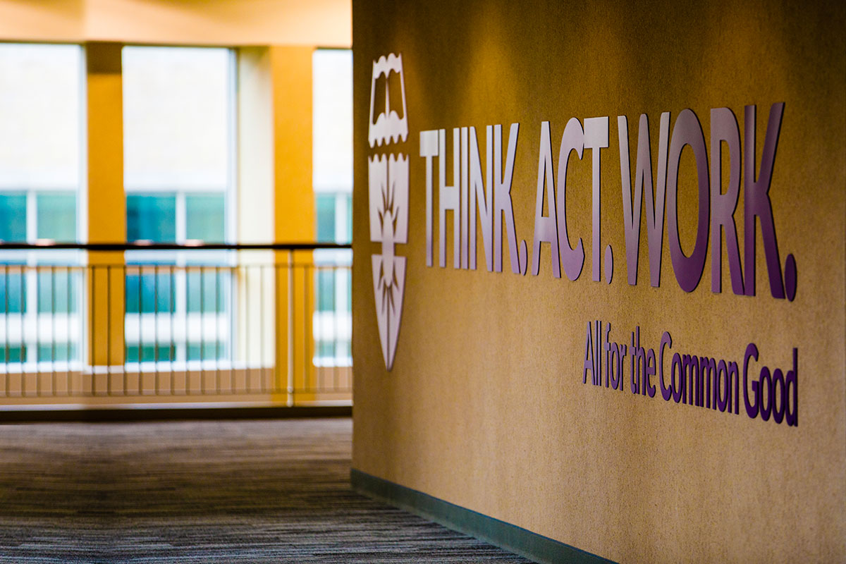 A sign reading "Think. Act. Work. All for the Common Good” is shown in the skyway.