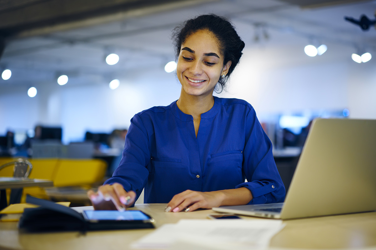 Cheerful individual on tablet in coworking space.