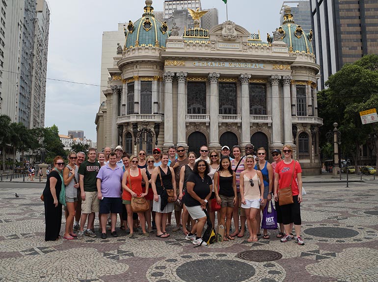 A group of students pose in front of a beautiful building.