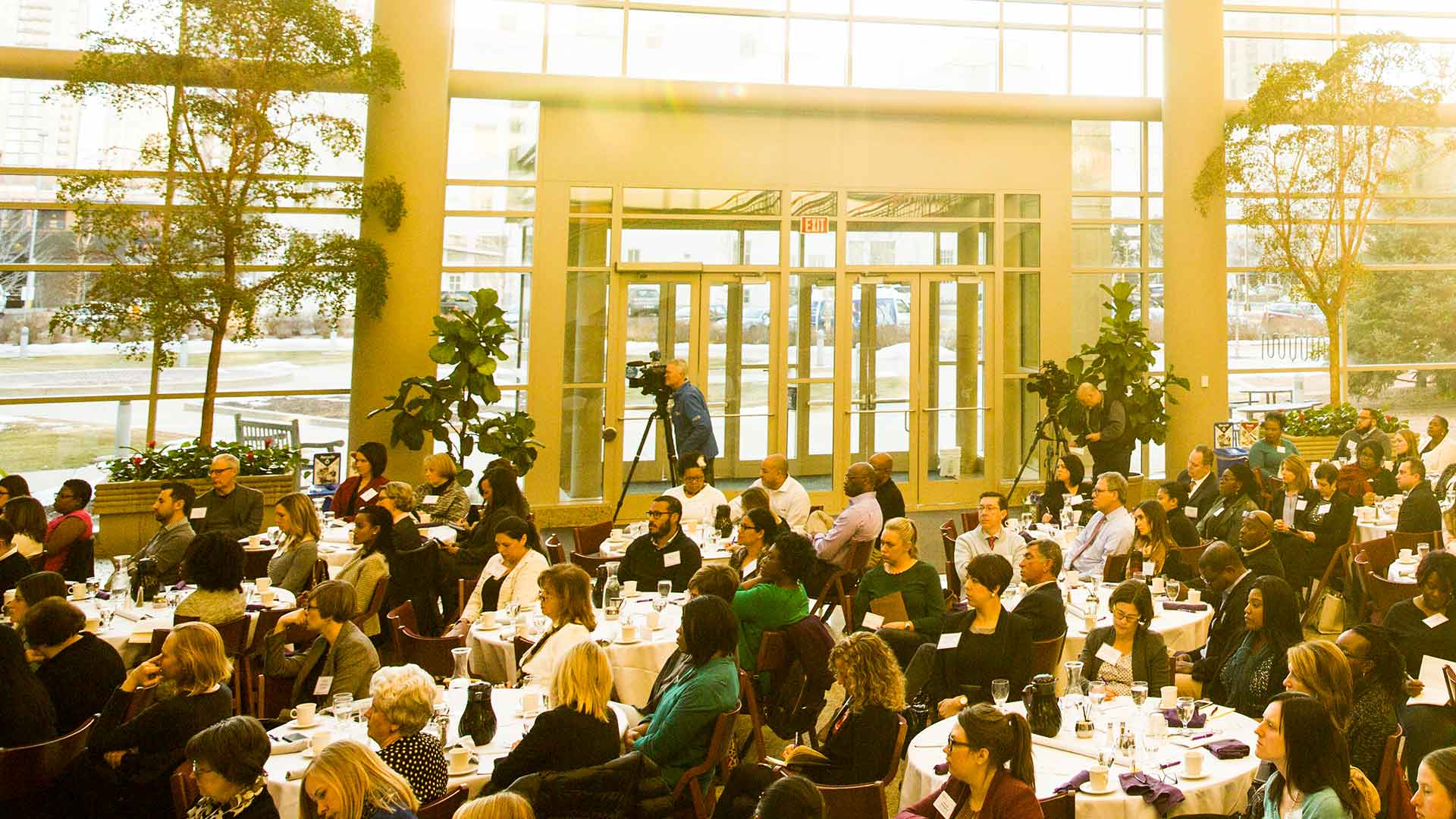Attendees listen to a speech over dinner at the Schulze Atrium.