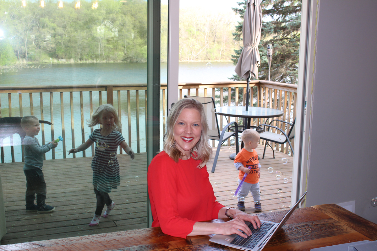 Tiffany Finley working at table with her children playing in the background