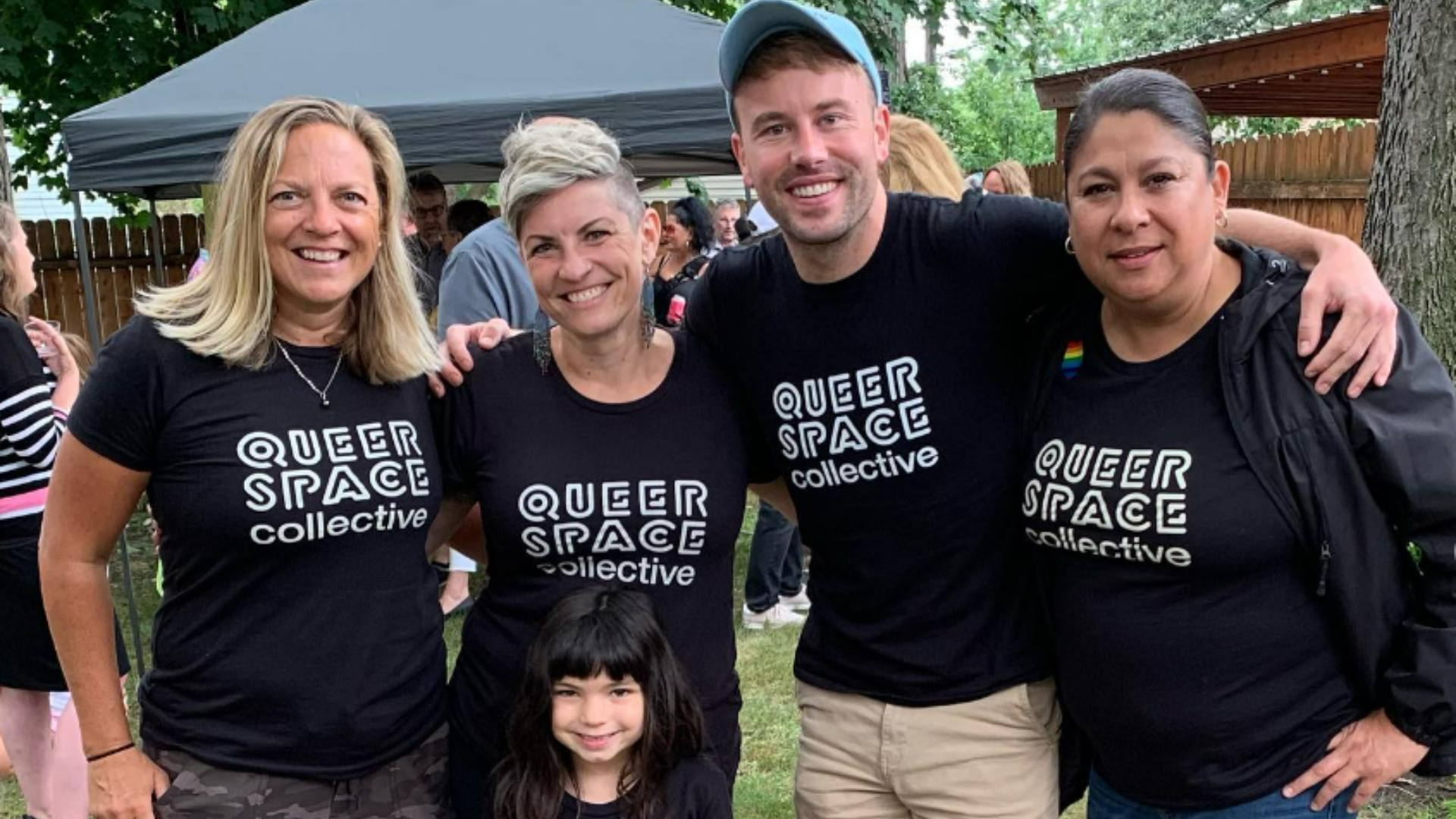 Group of people posing and smiling wearing QUEERSPACE collective black tshirts