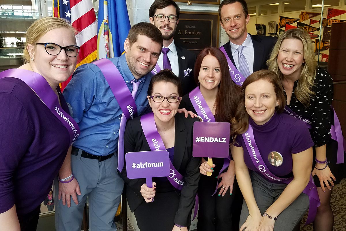 Bridget Rissman poses for a group photo with other professionals in front of a senate member's office. 